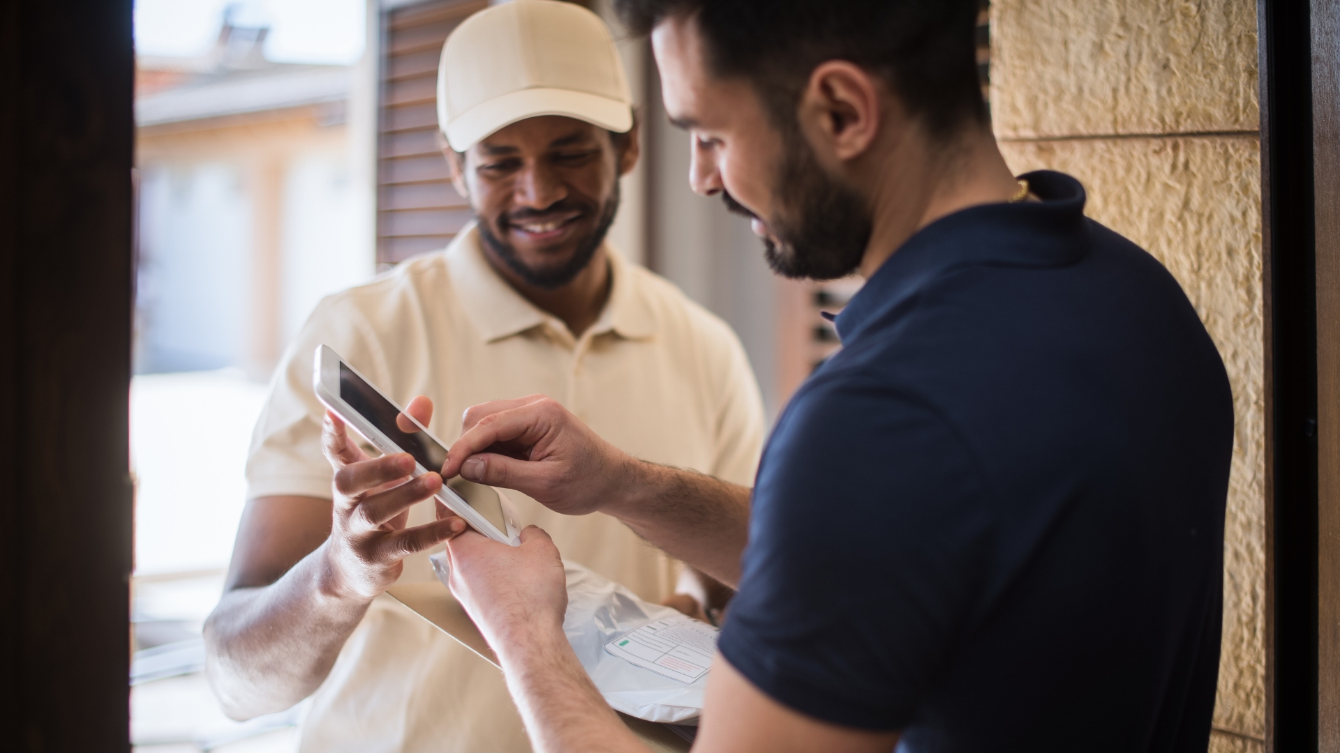 A delivery person and customer smiling as they confirm a package delivery using a handheld device