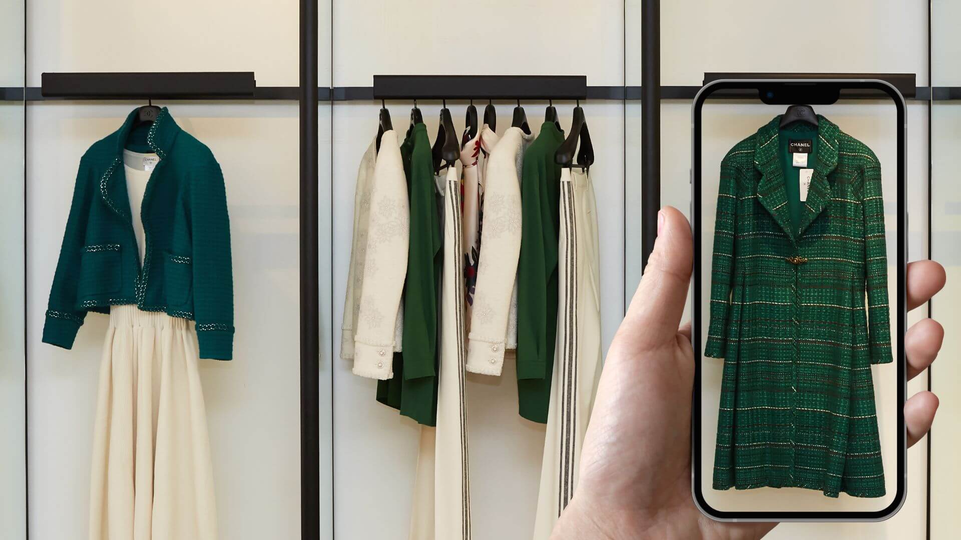 A hand holding a smartphone in front of a clothing rack, using visual search to identify a green coat in a store